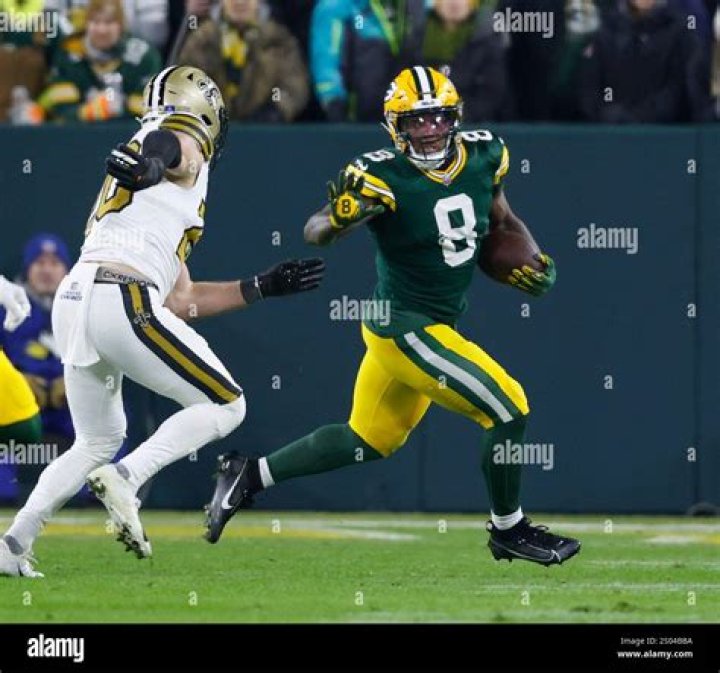 Josh Jacobs running with two Green Bay Packers behind him. 